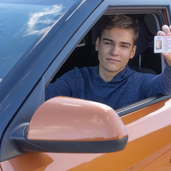 Ein junger Mann zeigt seinen Führerschein aus dem Autofenster